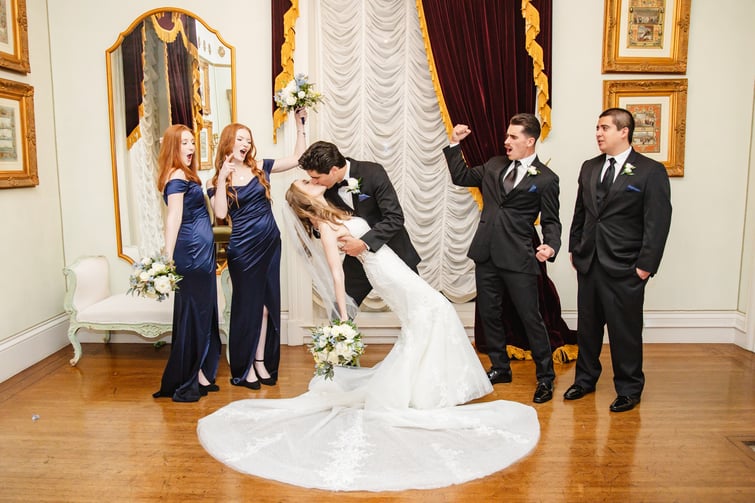 Couple kissing as wedding party cheers - Jefferson Street Mansion by Wedgewood Weddings