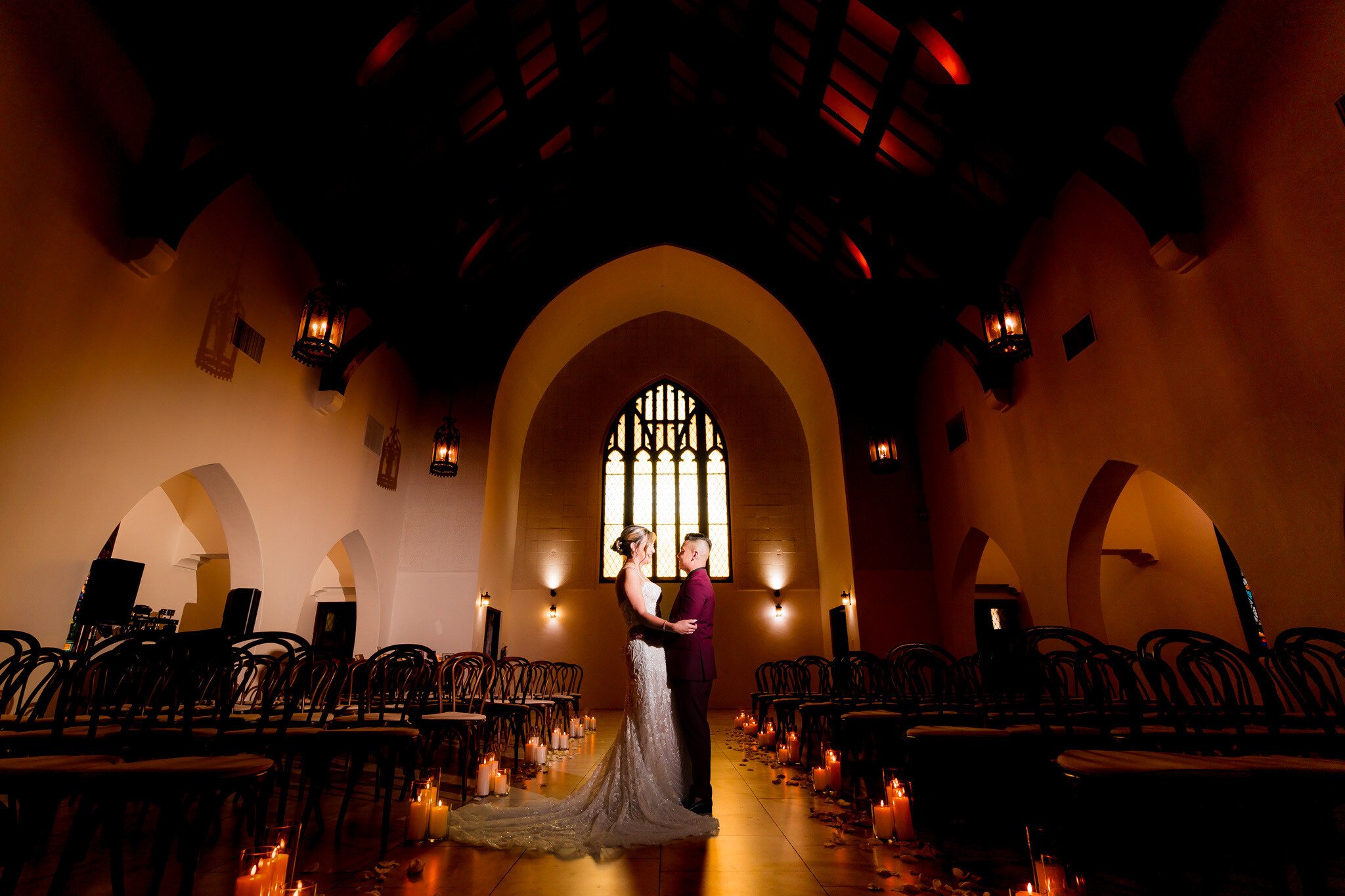 Silhouette of bride and groom in The Sanctuary's Cathedral with candlelit aisle and Gothic windows