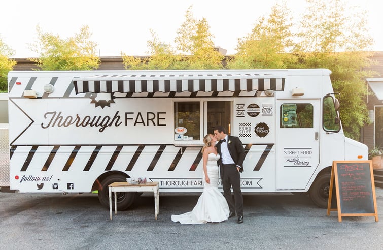 Bride and groom kissing in front of food truck