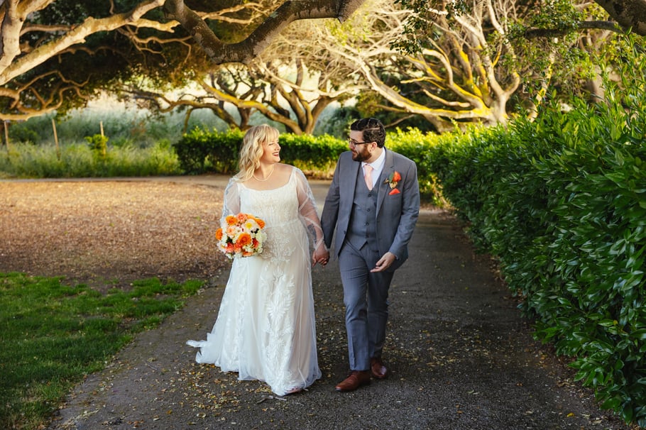 Newlyweds strolling through trees at Carmel Fields by Wedgewood Weddings