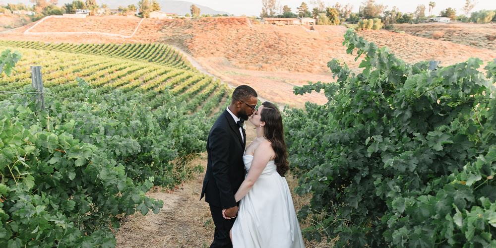 Couple kissing in vineyard at Bel Vino Winery by Wedgewood Weddings