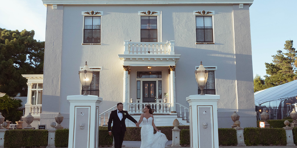 Bride and groom holding hands outside Jefferson Street Mansion in Benicia, CA