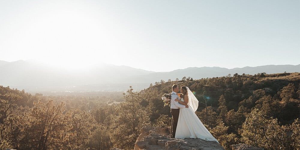 Newlyweds on large rock overlooking gorgeous mountains - Creekside Terrace by Wedgewood Weddings