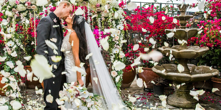 A couple on their wedding day sharing a moment in front of a water fountain at Cuvier Club by Wedgewood Weddings.