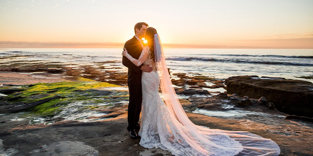 A couple embraces at sunset on the beach at Cuvier Club by Wedgewood Weddings