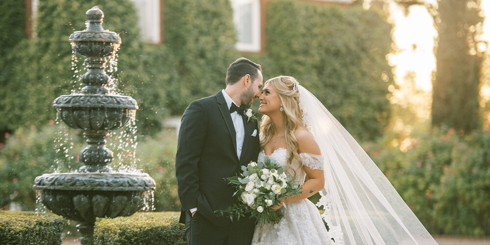 Newlyweds in front of fountains and lush greenery at Stonebridge Manor by Wedgewood Weddings