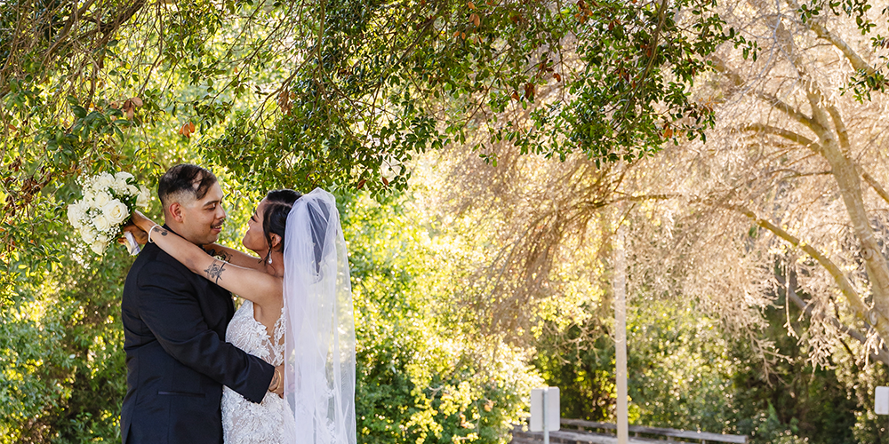 Newlyweds hugging by beautiful tree at Hiddenbrooke Hills by Wedgewood Weddings