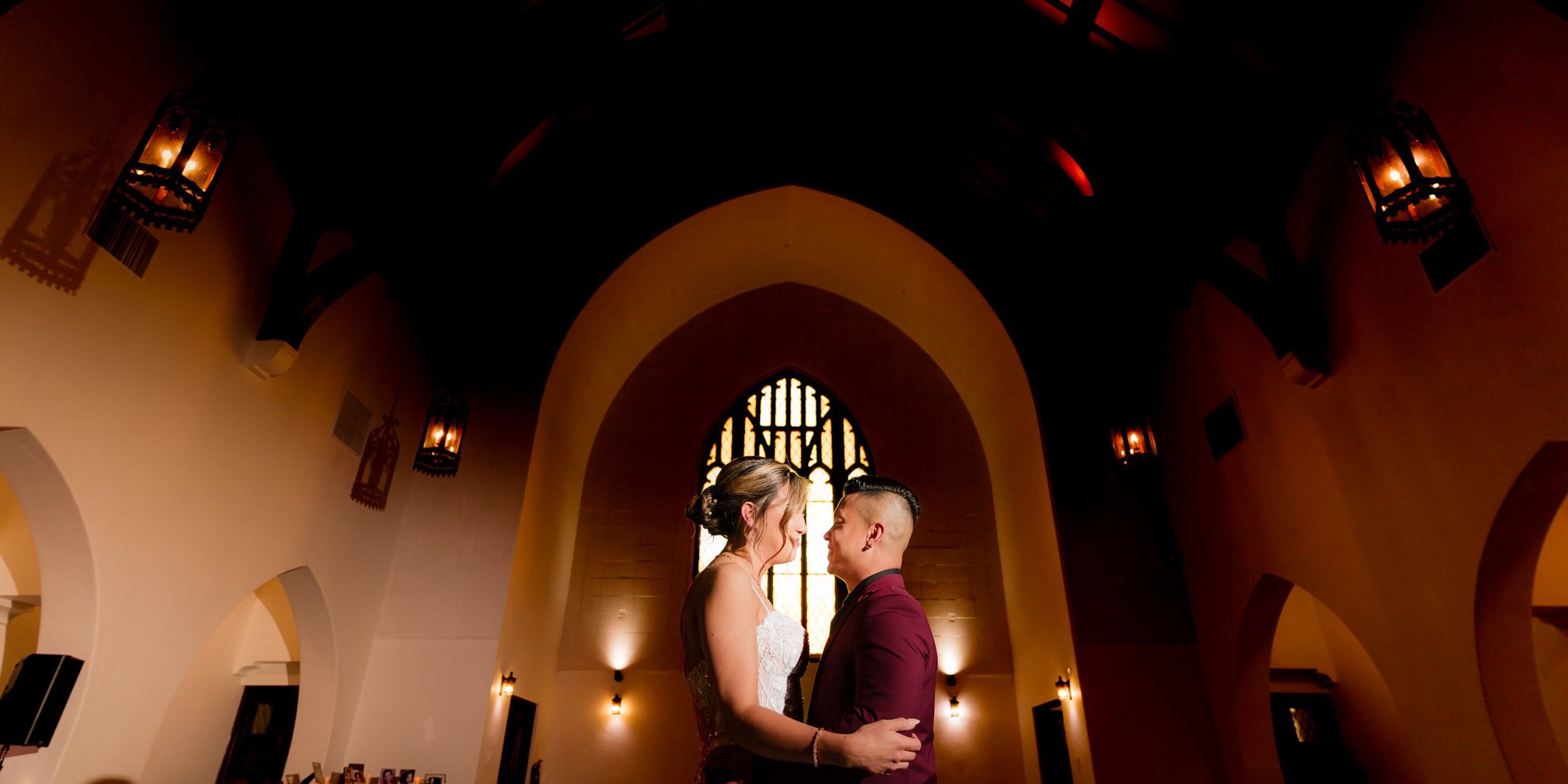 Silhouette of bride and groom in The Sanctuary's Cathedral with candlelit aisle and Gothic windows