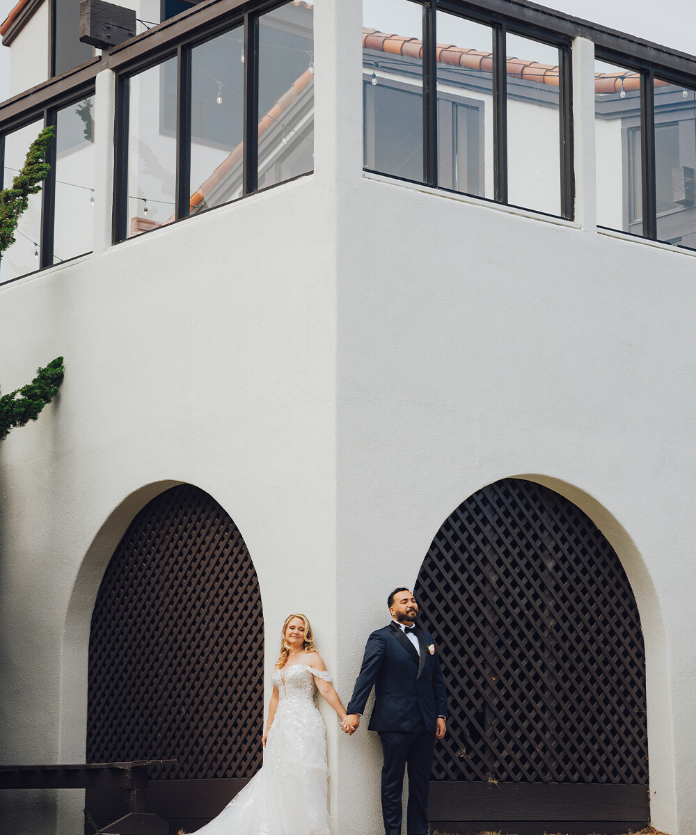 Couple posing in front of exterior of building- Carmel Fields by Wedgewood Weddings