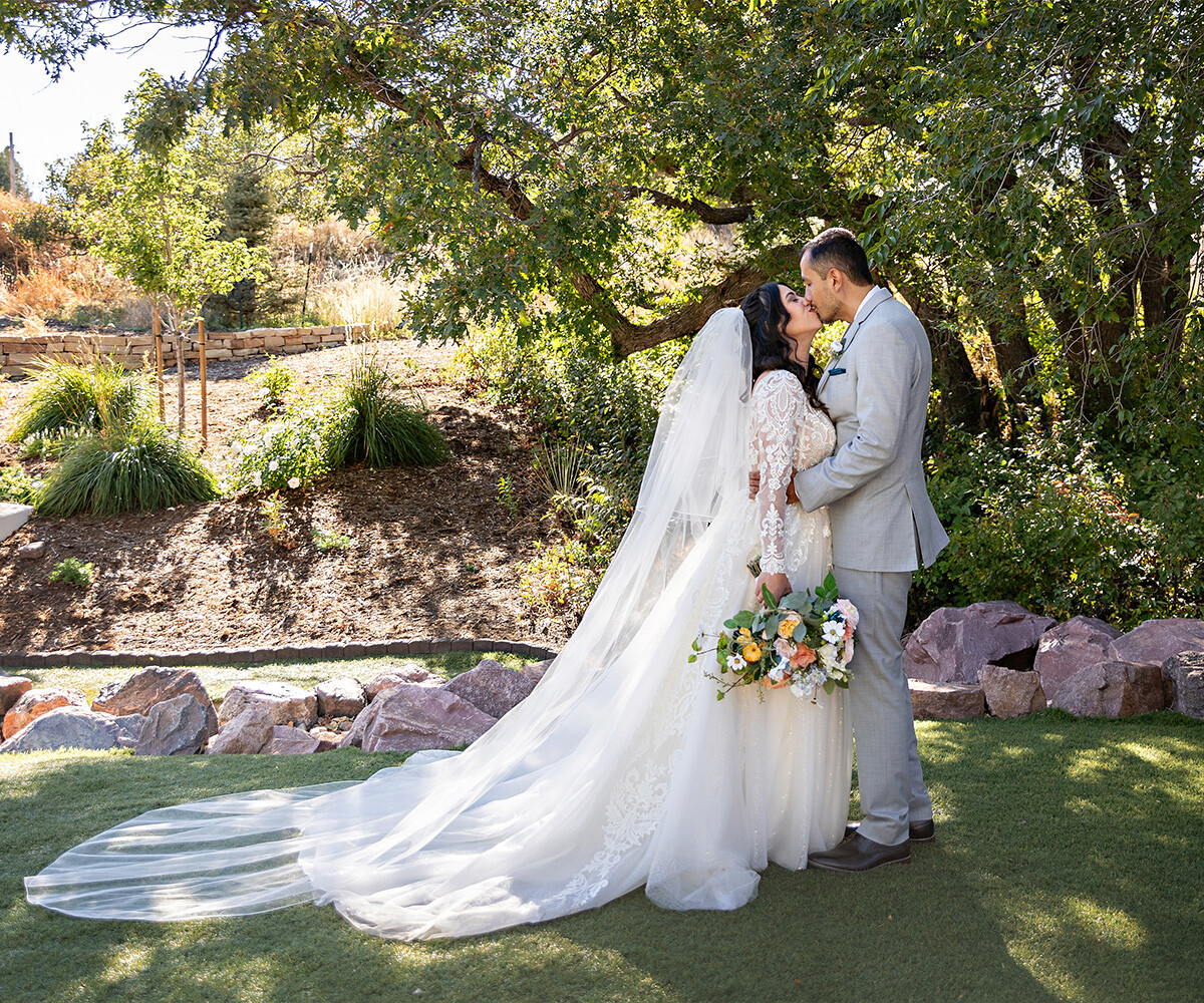 Couple kissing among lush greenery - Creekside Terrace by Wedgewood Weddings