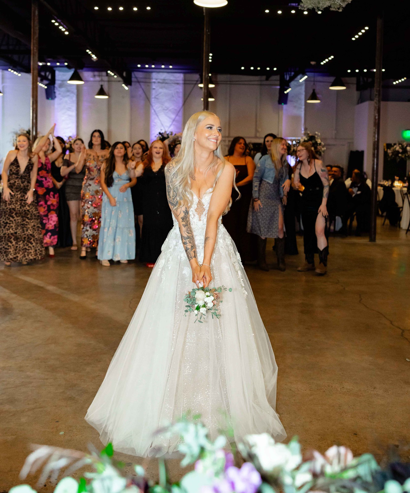 Bride in sparkling white ballgown preparing to toss bouquet to wedding guests at Phoenix industrial venue  Croft Downtown