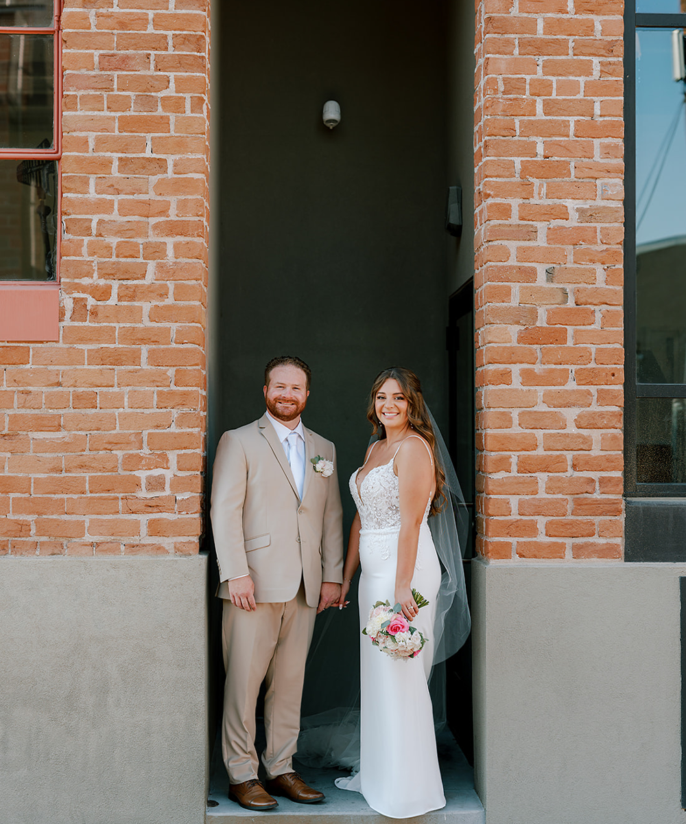 Newlyweds by brick building - Croft Downtown by Wedgewood Weddings