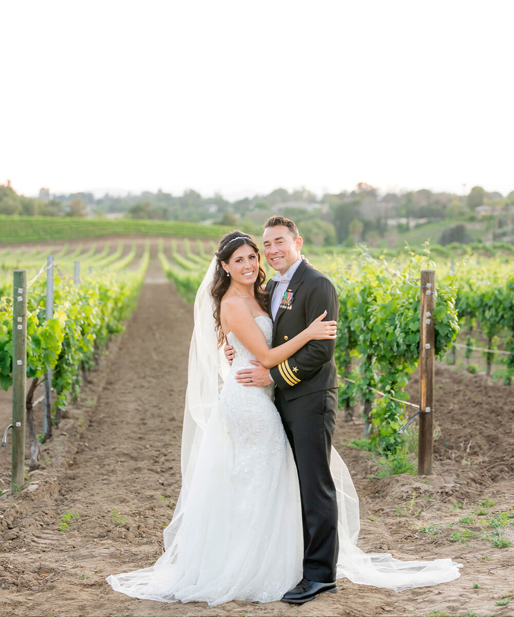 Couple posing in vines at Danza del Sol Winery by Wedgewood Weddings