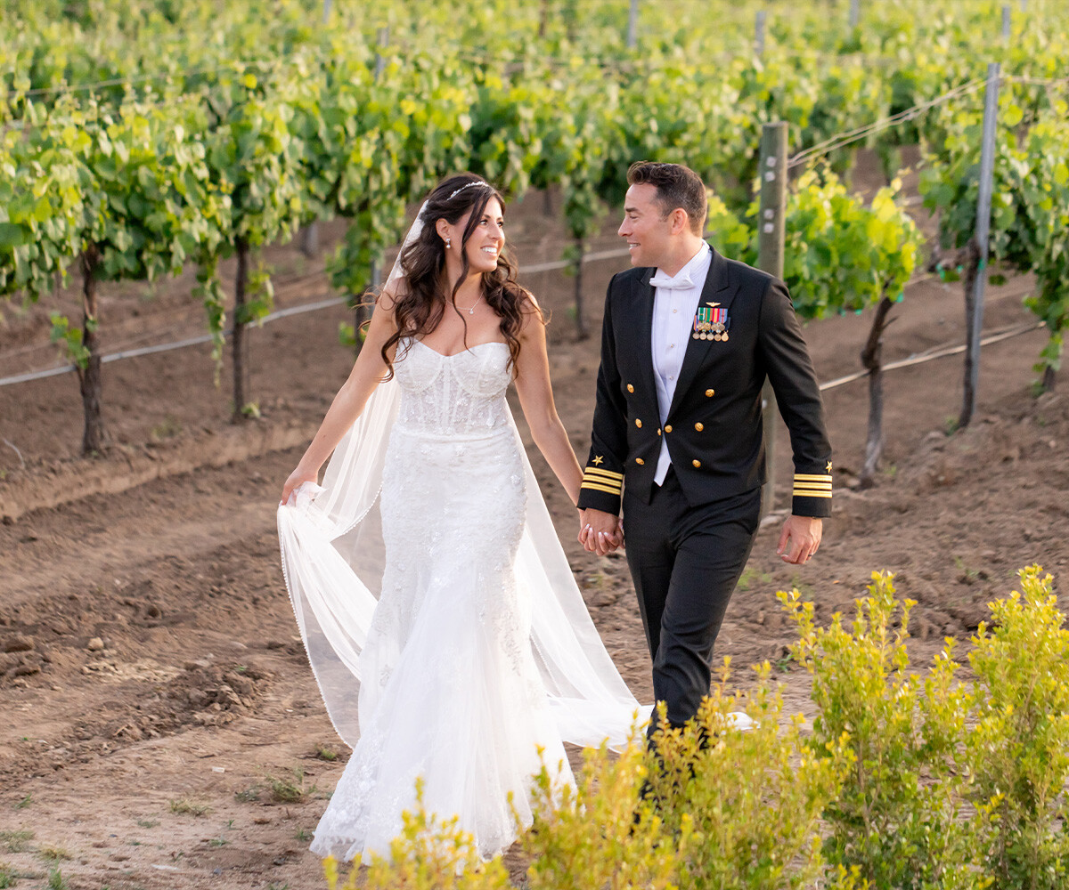 Happy couple and military groom walking through vines - Danza del Sol Winery by Wedgewood Weddings