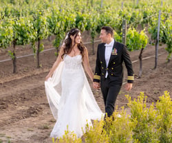 Happy couple and military groom walking through vines - Danza del Sol Winery by Wedgewood Weddings