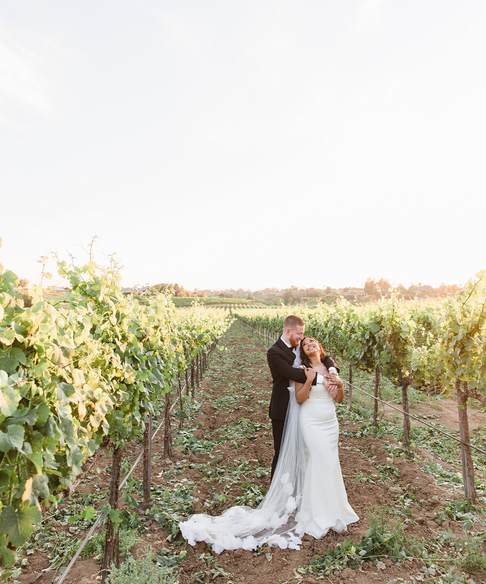 Happy newlyweds among vines at Danza del Sol Winery by Wedgewood Weddings