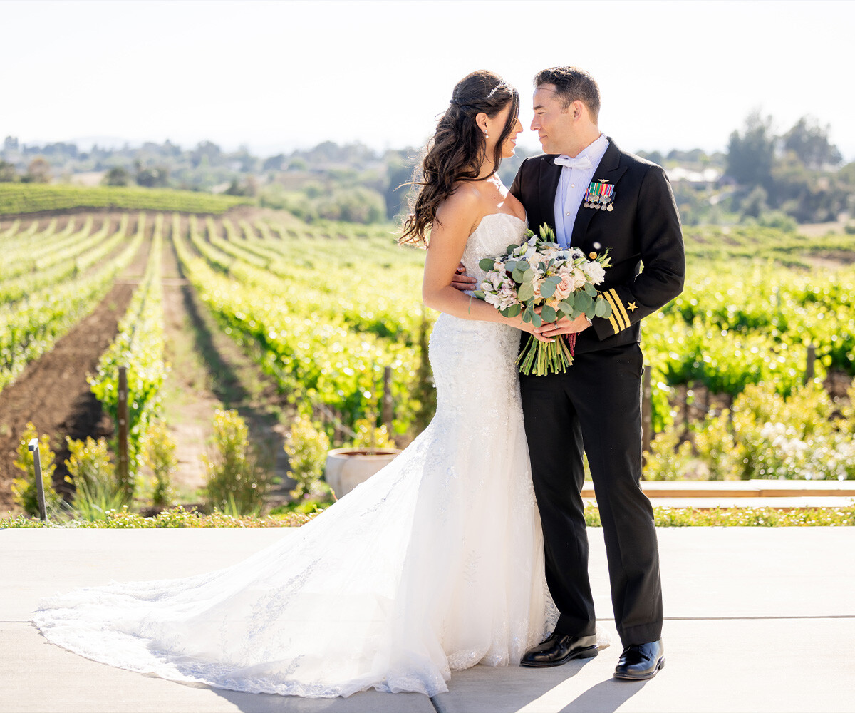 Newlyweds posing in front of vineyards - Danza del Sol Winery by Wedgewood Weddings