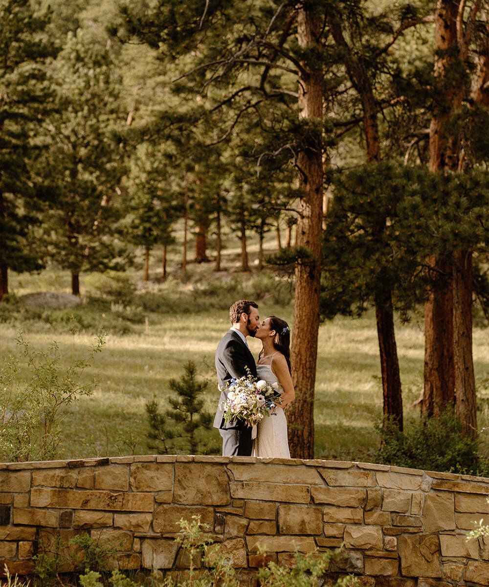 Couple kissing on stone bridge in woods - Della Terra by Wedgewood Weddings