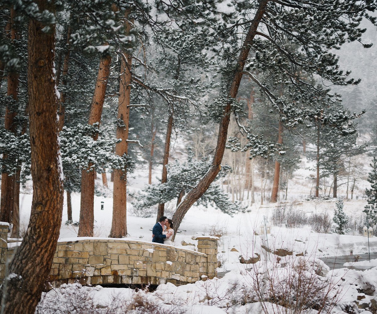 Newlyweds kissing on bridge in snow - Della Terra by Wedgewood Weddings