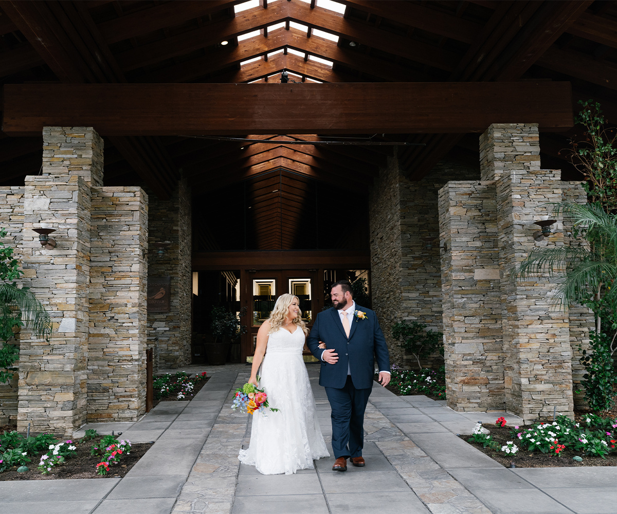 Bride and groom walking out of stone entrance to Dove Canyon by Wedgewood Weddings