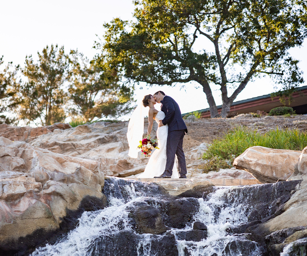 Couple kissing while standing on rocks above a small waterfall at Dove Canyon