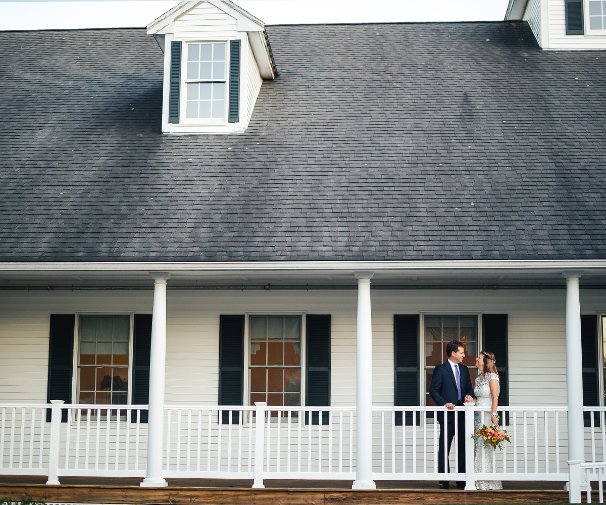 Couple posing on wraparound porch at Groveland Fairways by Wedgewood Weddings