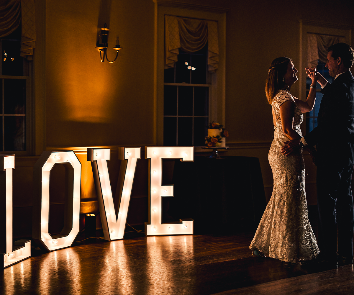 Happy couple dancing with marquee letters - Groveland Fairways by Wedgewood Weddings