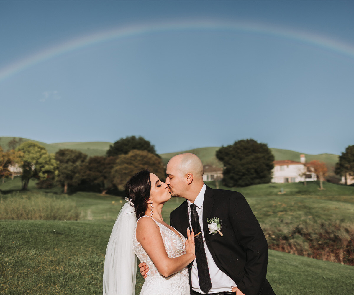 Couple kissing underneath rainbow - Hiddenbrooke Hills by Wedgewood Weddings