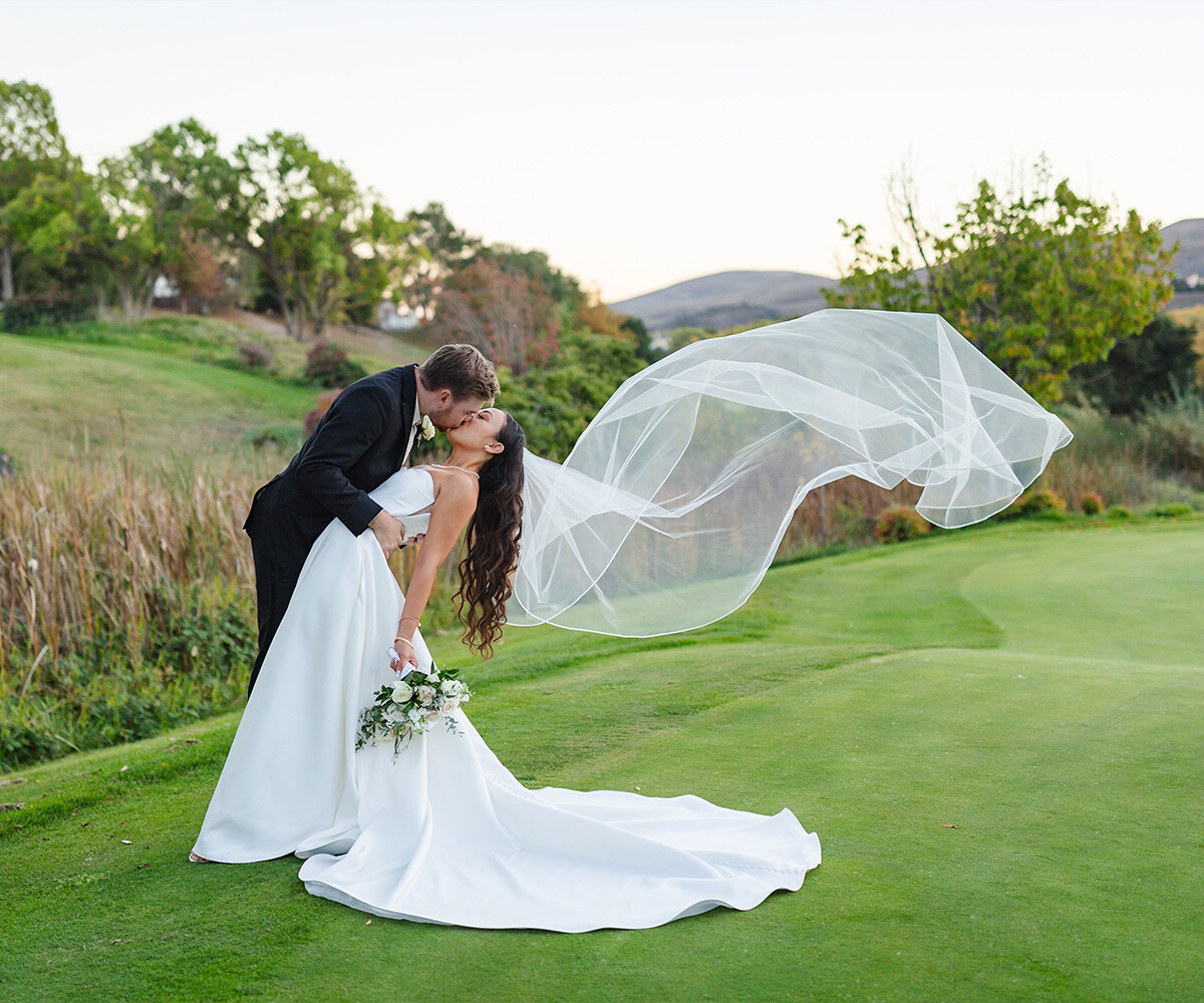 Happy newlyweds posing among greenery at Hiddenbrooke Hills by Wedgewood Weddings