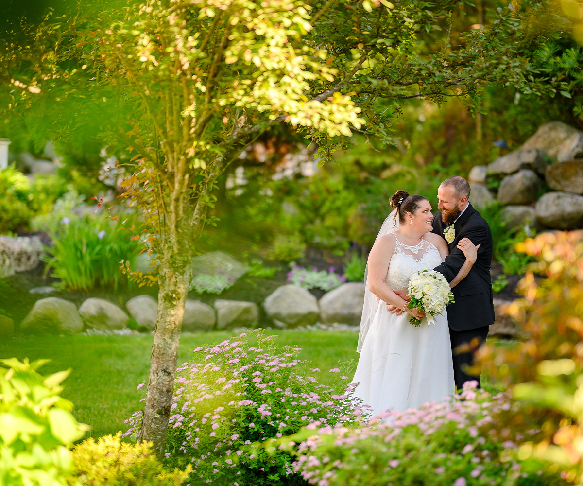 Happy couple posing in front of lush gardens - Miraval Gardens by Wedgewood Weddings