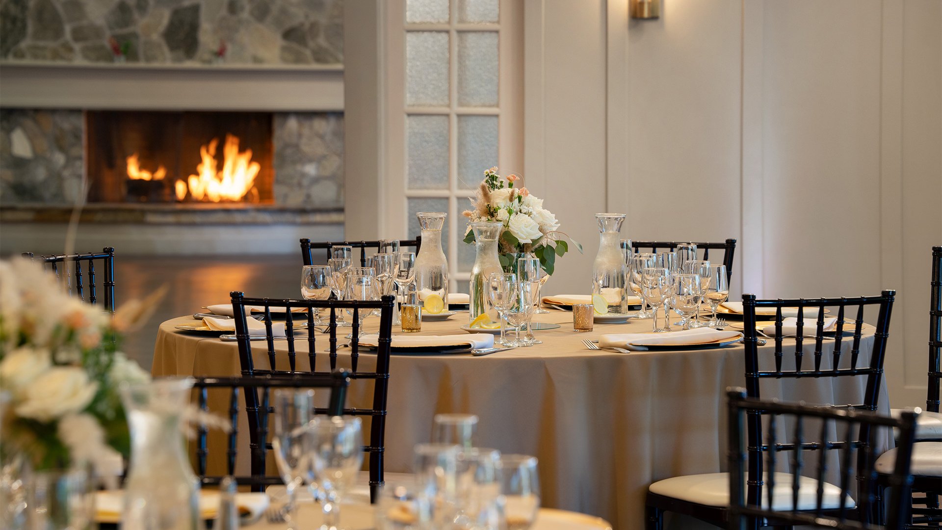 Intimate Table Setting Detail with Stone Fireplace Background and Floral Centerpieces