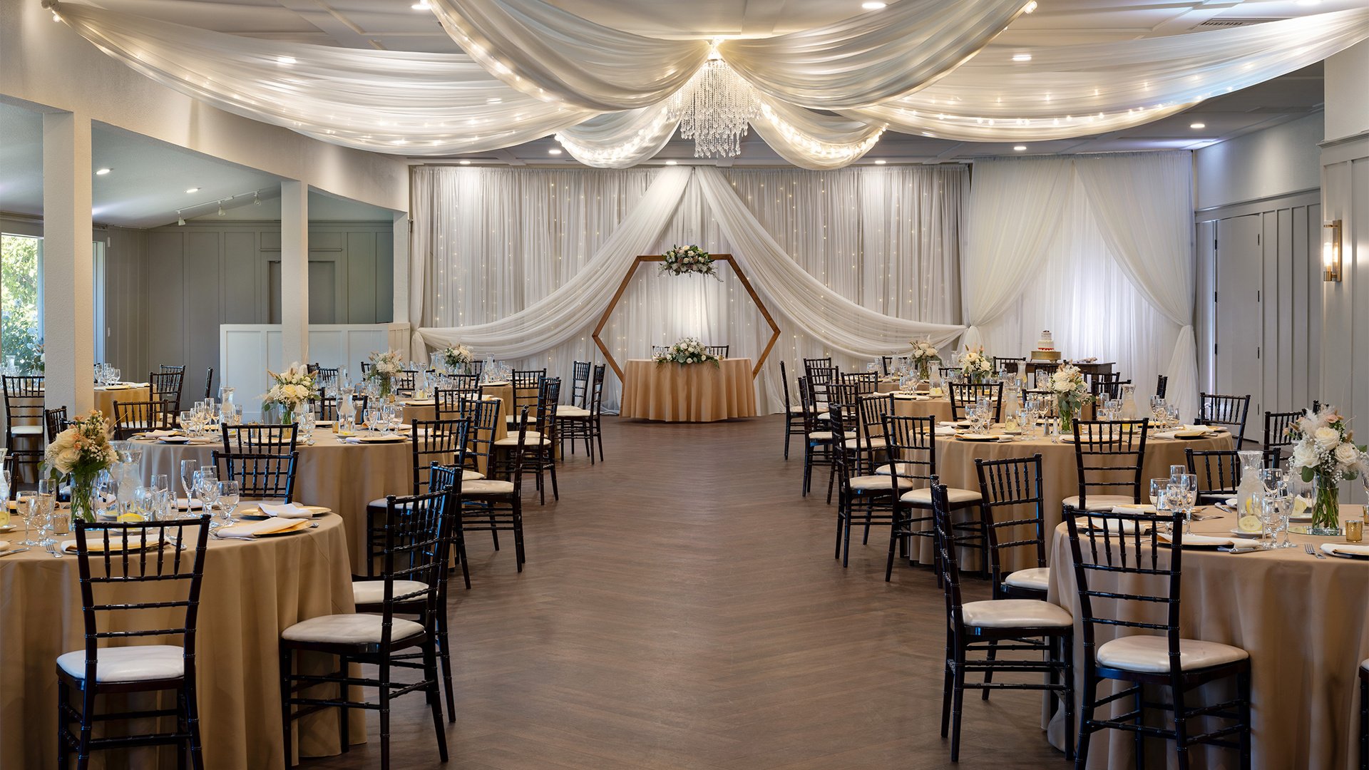 Wedding Reception Hall with Hexagonal Arch Backdrop and Elegant White Ceiling Draping