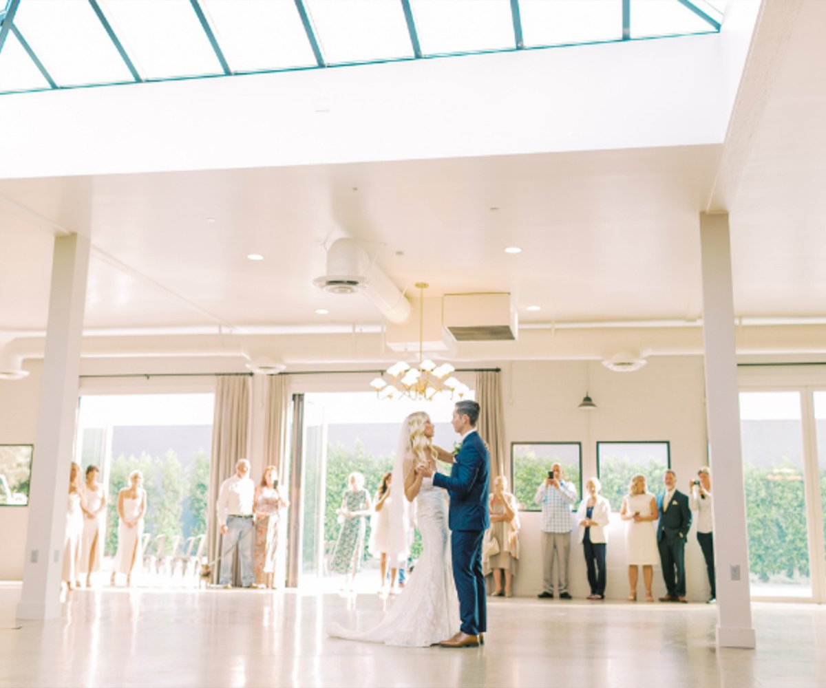 First dance in The Harper's light-filled Atrium with natural skylight, modern chandeliers, and floor-to-ceiling windows