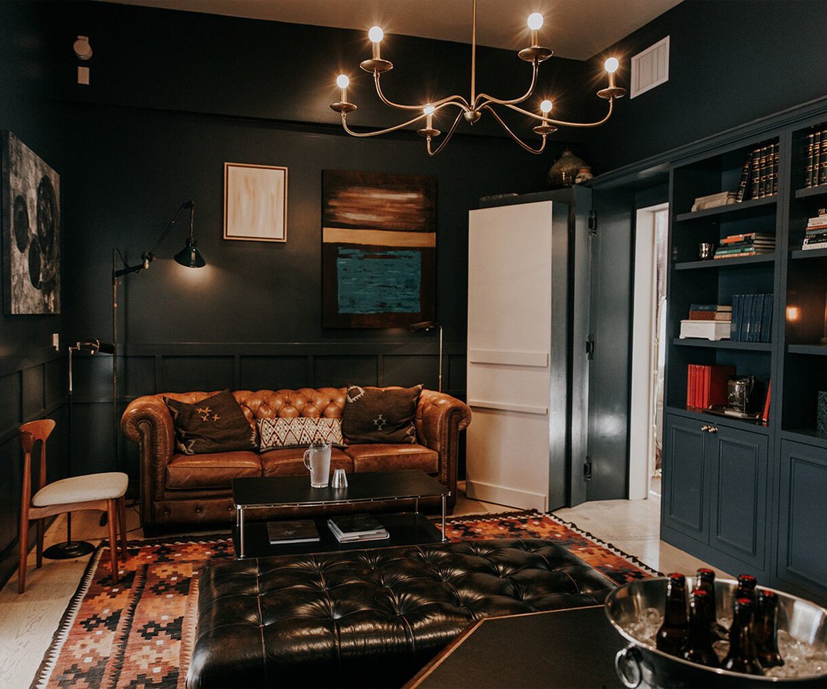 Stylish library lounge at The Harper with navy built-ins, leather furnishings, modern art, and geometric rug - perfect for wedding party preparations