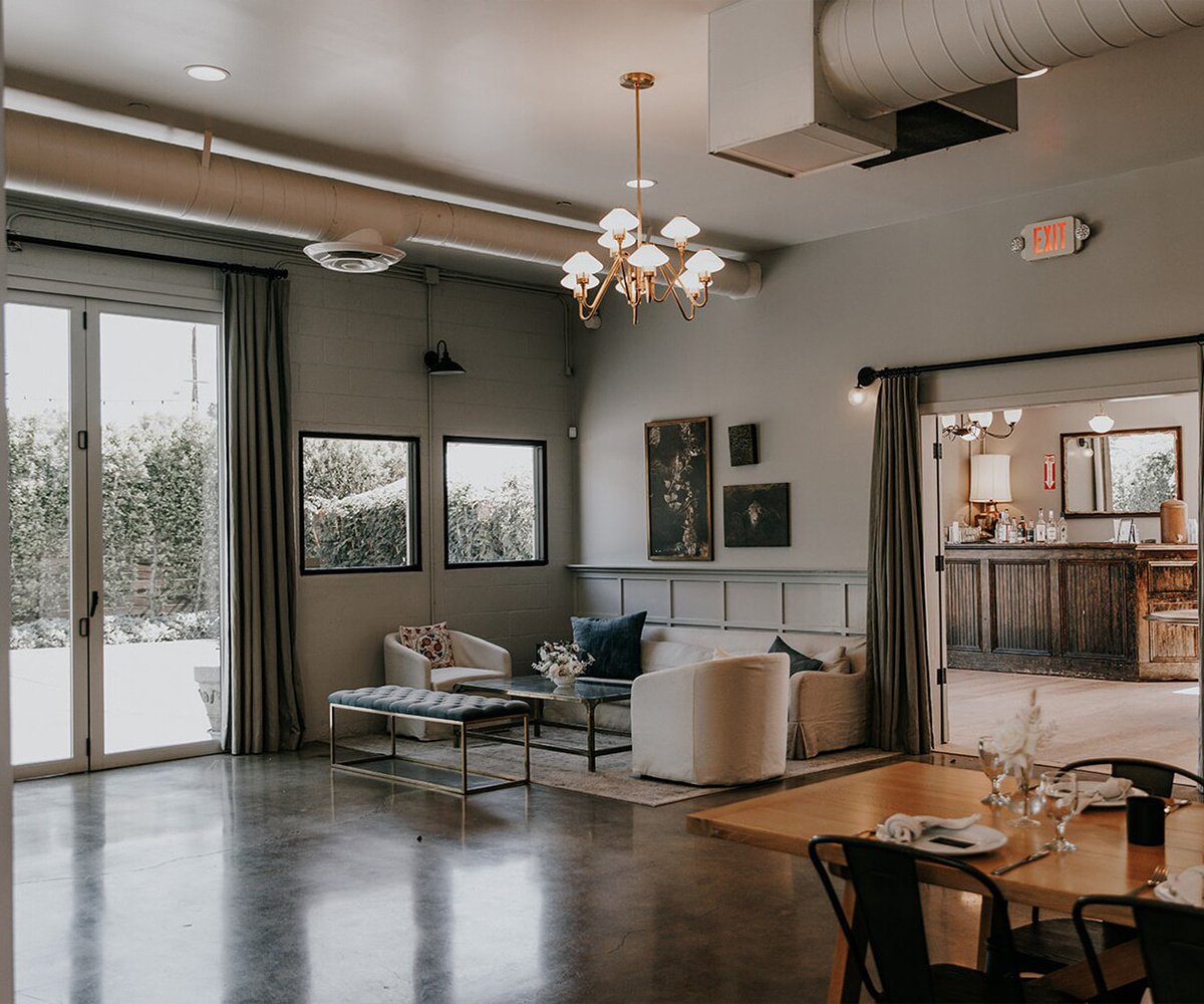 Modern bar lounge at The Harper wedding venue featuring brass chandelier, polished concrete floors, contemporary furniture, and vintage-inspired bar in Orange County