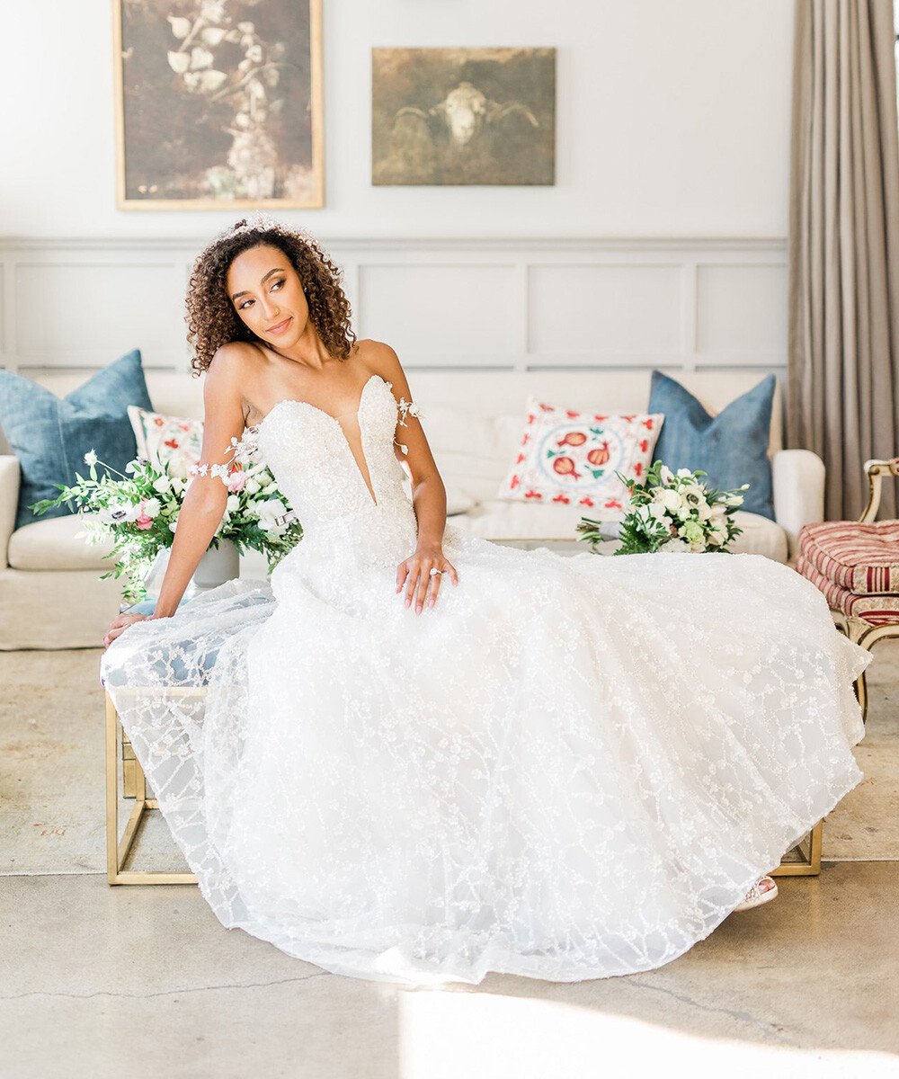 Bride in elegant  wedding dress with peach bouquet in The Harper's bright Sunroom featuring modern wall paneling and French-inspired decor