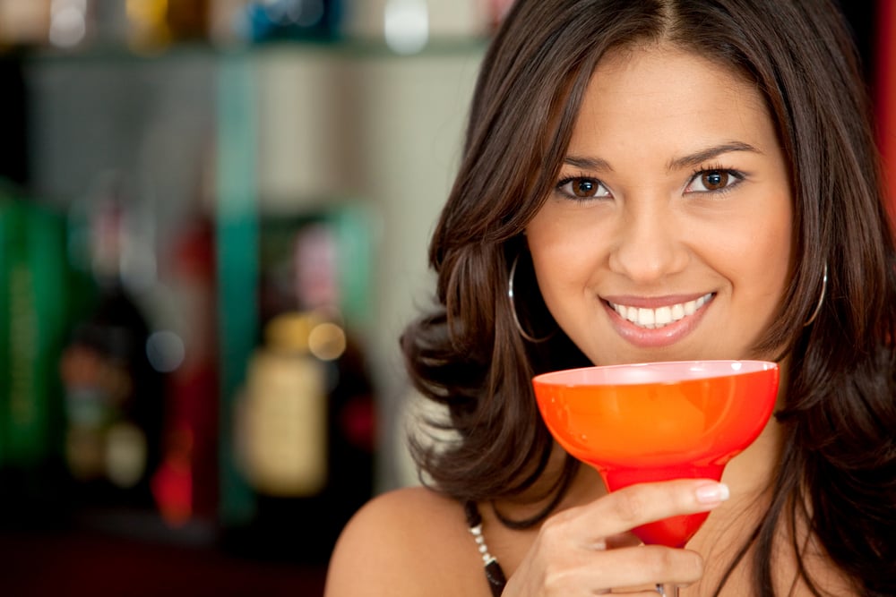 Beautiful woman portrait with a glass drinking a cocktail at a bar