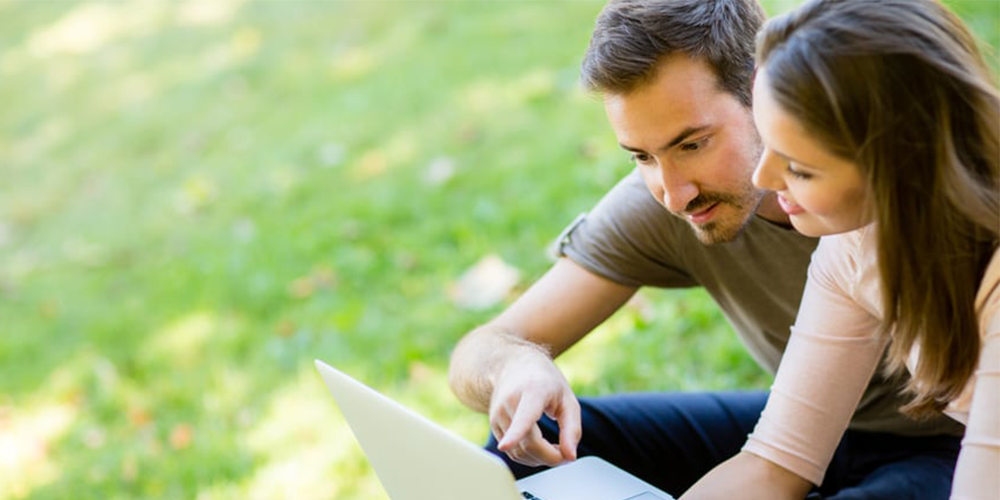 couple outside looking at laptop