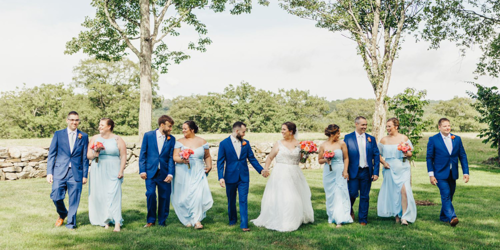 Wedding party walking in the lush green meadows of Fern Hill Barn 