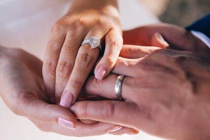 Close-up of a couple's hands with engagement and wedding rings, symbolizing a new commitment