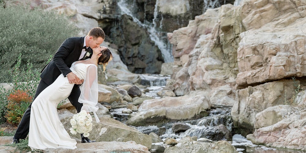 Couple embracing by dramatic waterfall at Dove Canyon by Wedgewood Weddings